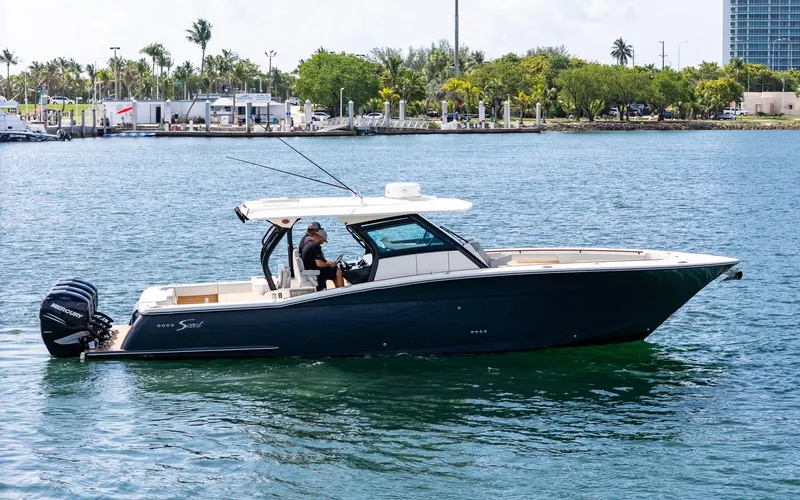 Slide: The Image of 2020 Scout 380 LXF boat cruising on a sunny day near a marina. - 4