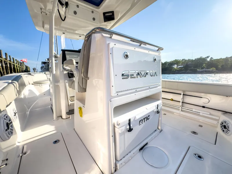 Slide: The Image of 2022 Sea Fox 288 Commander boat interior with seating and storage, docked by the water. - 24