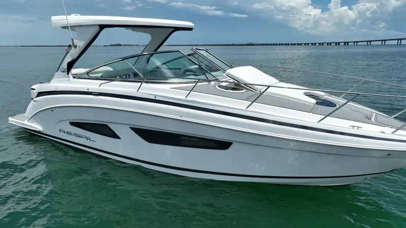 The Image of 2021 Regal 33 XO boat cruising on open water with a bridge in the background. - 0