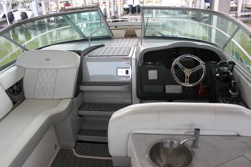 Slide: The Image of 2021 Regal 33 XO boat interior with helm, seating, and sink in a marina setting. - 19