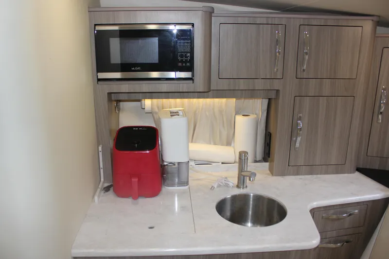 Slide: The Image of 2021 Regal 33 XO yacht kitchenette with microwave, sink, and storage cabinets. - 43