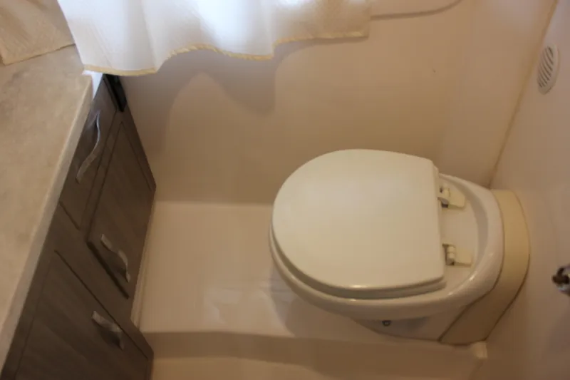 Slide: The Image of Bathroom interior of 2021 Regal 33 XO boat, featuring a compact toilet and storage cabinets. - 48