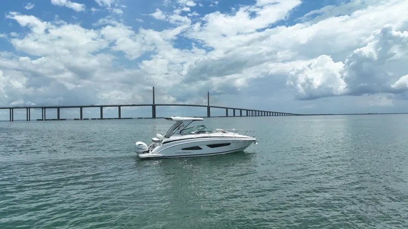 Slide: The Image of 2021 Regal 33 XO boat on water with bridge and cloudy sky background. - 5