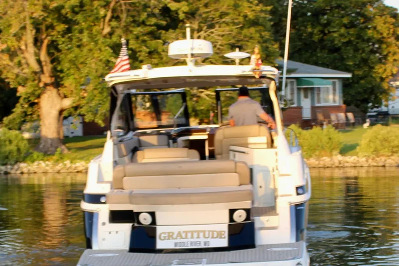 Slide: The Image of 2015 Regal 35 Sport Coupe boat on water, rear view, with American flags. - 15