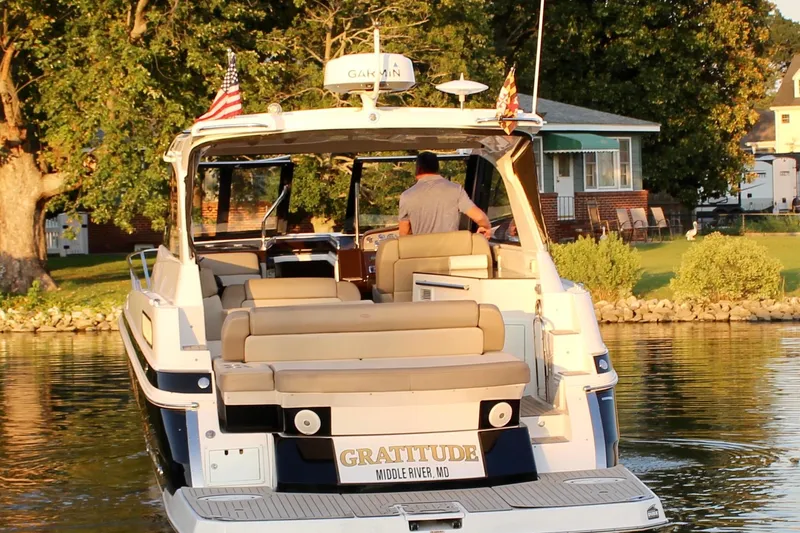 Slide: The Image of 2015 Regal 35 Sport Coupe boat on water near a lakeside house. - 16