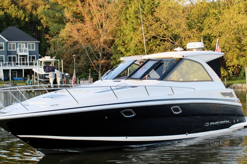 Slide: The Image of 2015 Regal 35 Sport Coupe boat on a serene lake near a house. - 19