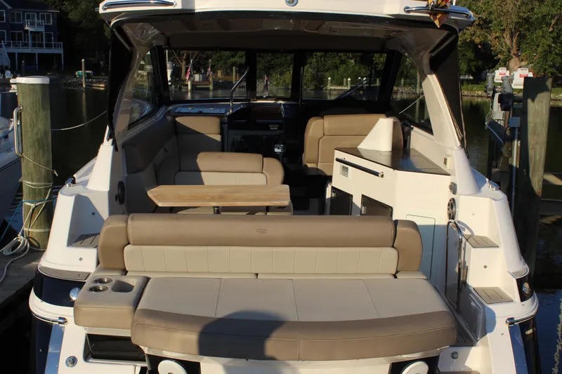 Slide: The Image of 2015 Regal 35 Sport Coupe boat interior with seating and table, docked at marina. - 24