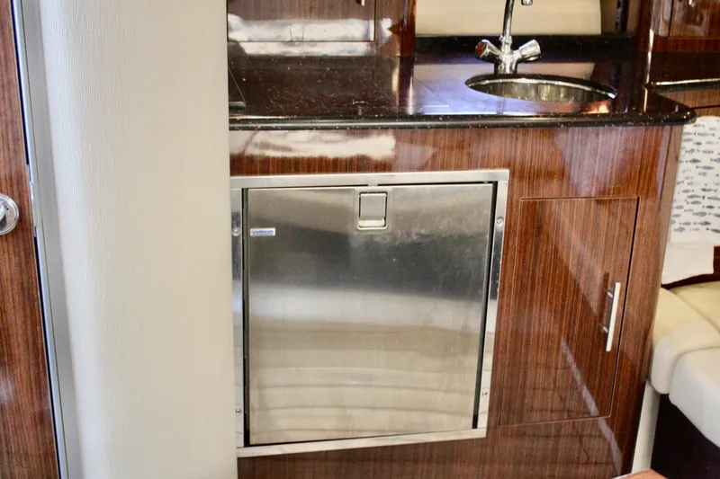 Slide: The Image of 2015 Regal 35 Sport Coupe interior with wood cabinetry and stainless steel fridge. - 58