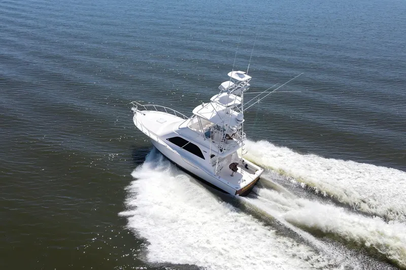 Slide: The Image of 2005 Cabo 40 Flybridge yacht cruising on open water, creating a wake. - 106