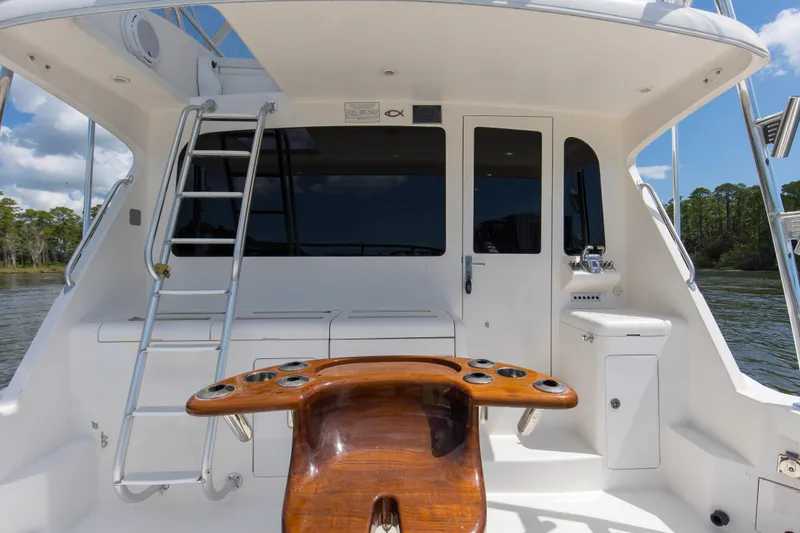 Slide: The Image of 2005 Cabo 40 Flybridge yacht cockpit with ladder, wooden table, and storage compartments. - 13