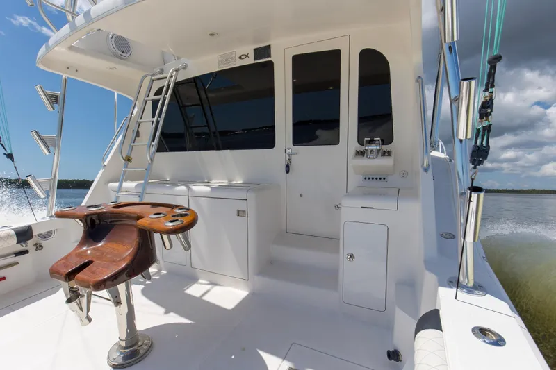 Slide: The Image of 2005 Cabo 40 Flybridge yacht deck with fishing chair and ladder under clear sky. - 3