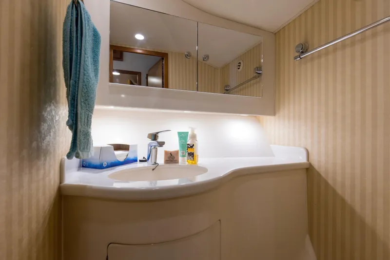Slide: The Image of Bathroom vanity in 2005 Cabo 40 Flybridge yacht with striped wallpaper and mirror cabinet. - 50