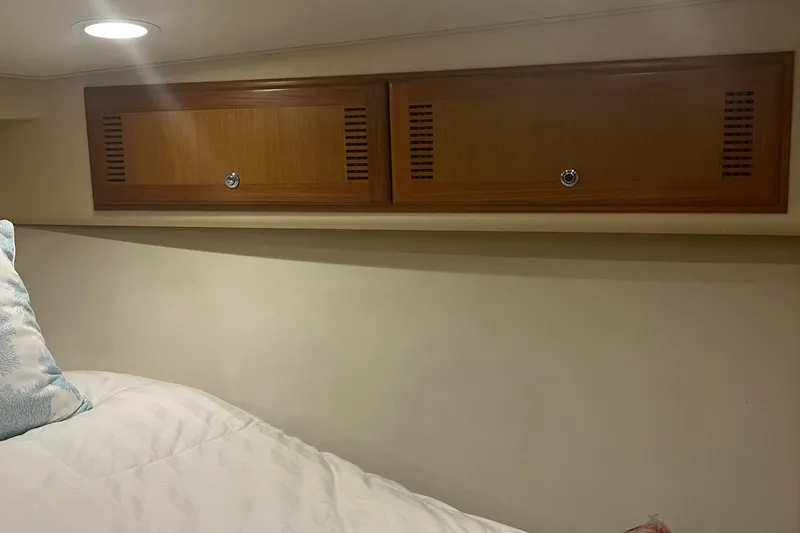 Slide: The Image of 2005 Cabo 40 Flybridge interior with wooden cabinets and cozy bedding. - 54