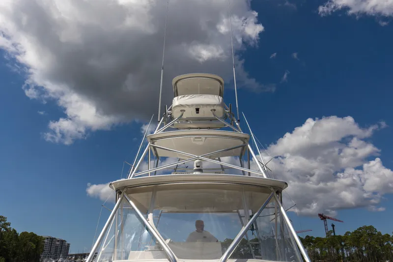 Slide: The Image of 2005 Cabo 40 Flybridge yacht under cloudy blue sky, showcasing its towering structure. - 64