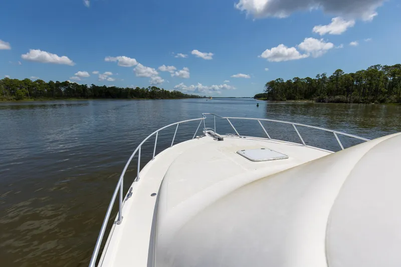 Slide: The Image of Bow view of 2005 Cabo 40 Flybridge yacht cruising on a serene river. - 65