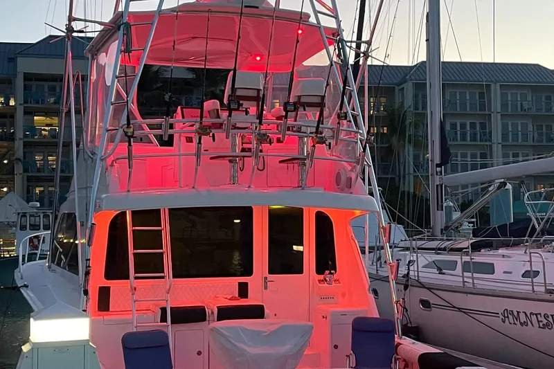 Slide: The Image of 2005 Cabo 40 Flybridge yacht with red lighting, docked at marina during evening. - 7