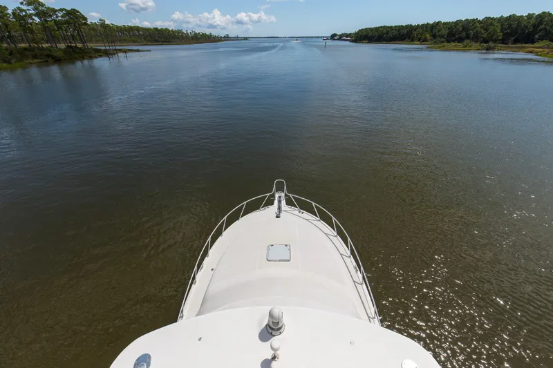 Slide: The Image of Bow view of 2005 Cabo 40 Flybridge yacht navigating a serene river. - 70