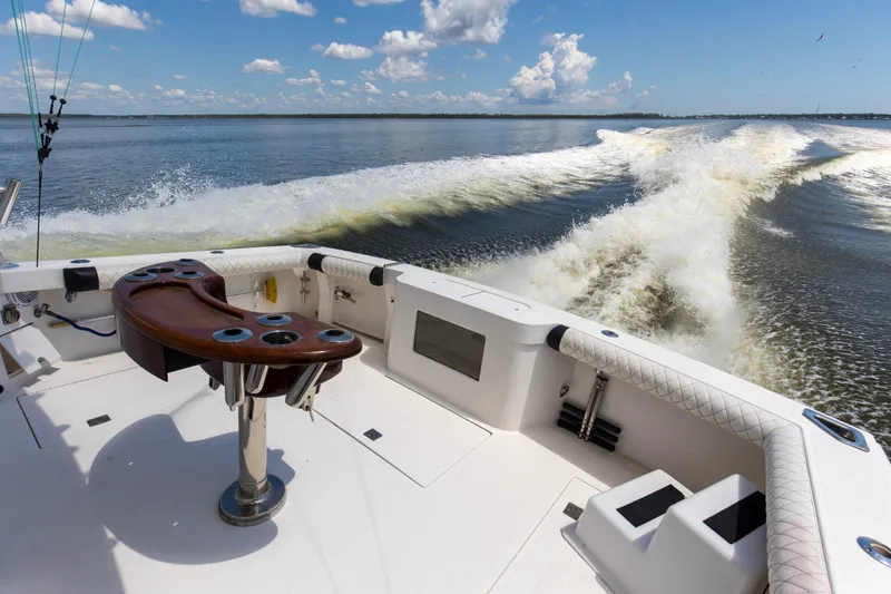 Slide: The Image of 2005 Cabo 40 Flybridge boat cruising on open water, featuring a spacious deck and fishing rod holders. - 76