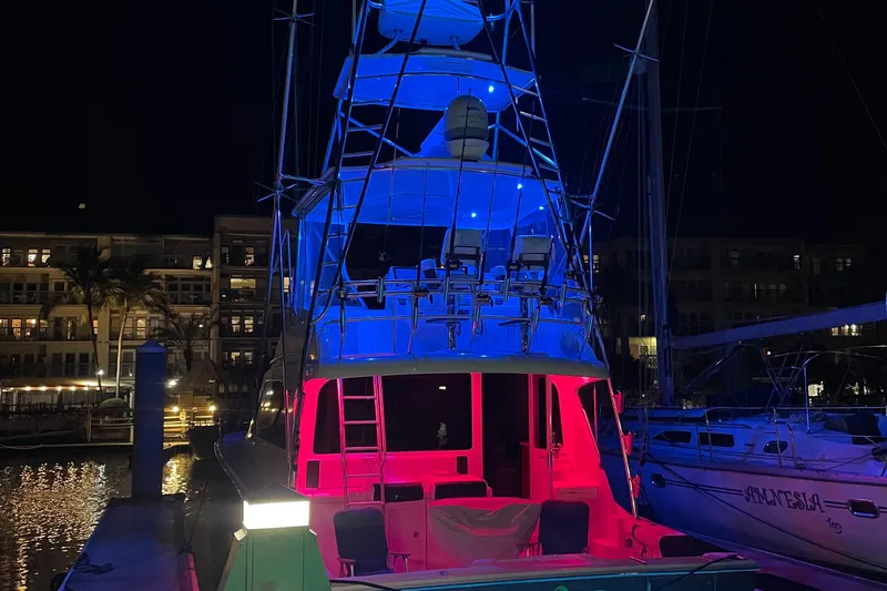 Slide: The Image of 2005 Cabo 40 Flybridge yacht illuminated with vibrant blue and red lights at night. - 8