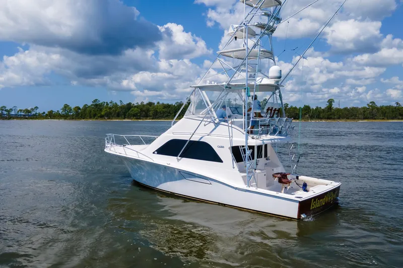 Slide: The Image of 2005 Cabo 40 Flybridge yacht cruising on a scenic waterway under a blue sky. - 83