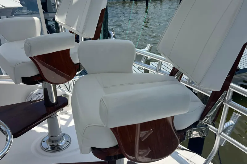 Slide: The Image of Luxurious seating on a 2005 Cabo 40 Flybridge yacht, featuring white cushions and wooden accents. - 94