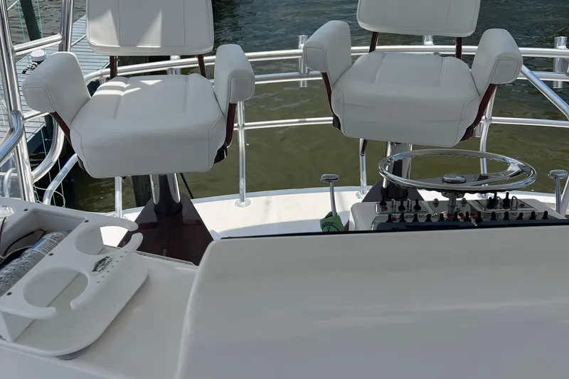 Slide: The Image of 2005 Cabo 40 Flybridge helm with dual white captain chairs and control panel. - 95