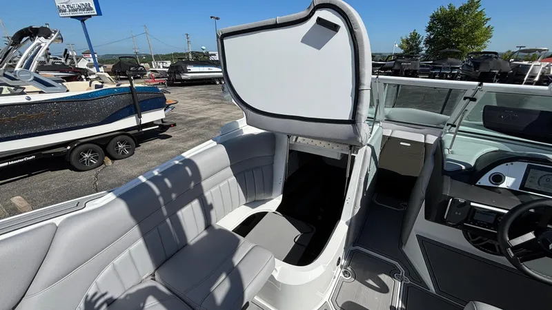 Slide: The Image of 2025 MB B52 25 Alpha boat interior with open storage compartment, gray seating, and dashboard. - 25