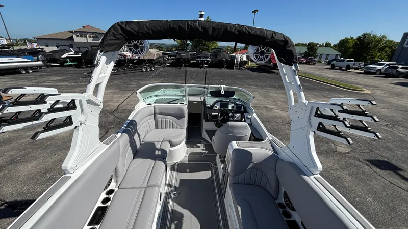 Slide: The Image of 2025 MB B52 25 Alpha boat interior with seating and wakeboard racks, parked outdoors. - 8