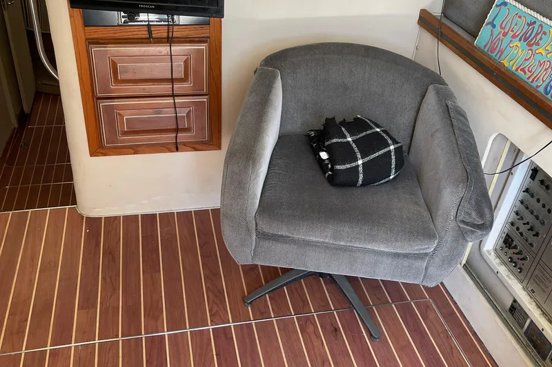 Slide: The Image of Gray swivel chair with plaid blanket on wooden floor in 1988 Trojan 12 Meter Convertible. - 38