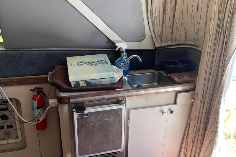 Slide: The Image of 1988 Trojan 12 Meter Convertible boat kitchen with sink, cleaning supplies, and fire extinguisher. - 39