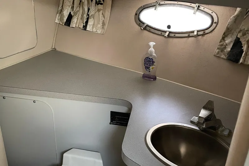 Slide: The Image of 1988 Trojan 12 Meter Convertible yacht bathroom with sink, countertop, and porthole window. - 46