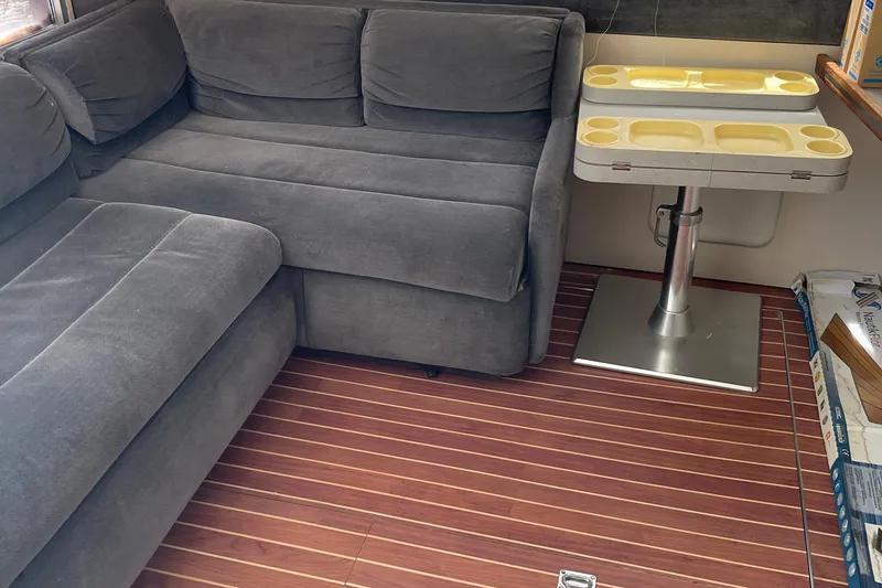 Slide: The Image of 1988 Trojan 12 Meter Convertible interior with gray sofa, wooden floor, and compact table. - 35