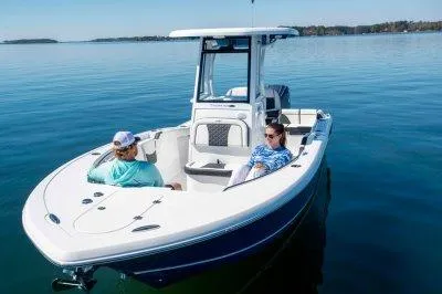 Slide: The Image of 2026 Tidewater 232 LXF boat on calm water with two people relaxing onboard. - 3