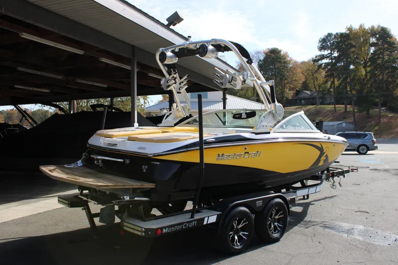 Slide: The Image of 2013 MasterCraft X-2 boat on trailer, yellow and black design, parked outdoors. - 19