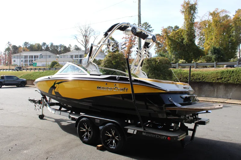 Slide: The Image of 2013 MasterCraft X-2 boat in yellow and black on a trailer, parked outdoors. - 22