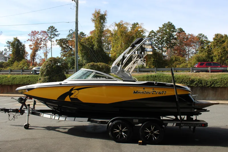 Slide: The Image of 2013 MasterCraft X-2 boat in yellow and black on a trailer, parked outdoors. - 23
