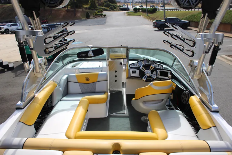 Slide: The Image of 2013 MasterCraft X-2 boat interior with yellow and white seating, sleek dashboard, and wakeboard racks. - 25