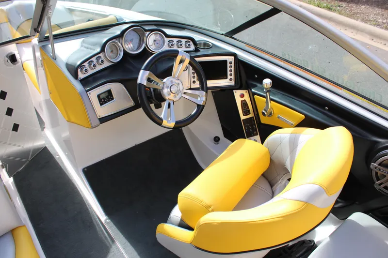 Slide: The Image of 2013 MasterCraft X-2 boat interior with yellow and white seating, modern dashboard, and steering wheel. - 28