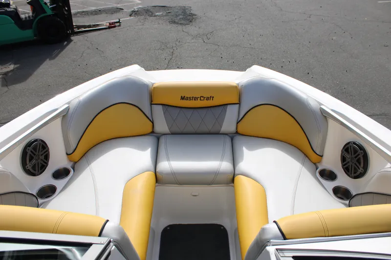 Slide: The Image of 2013 MasterCraft X-2 boat interior with yellow and white seating, featuring speakers and cup holders. - 32