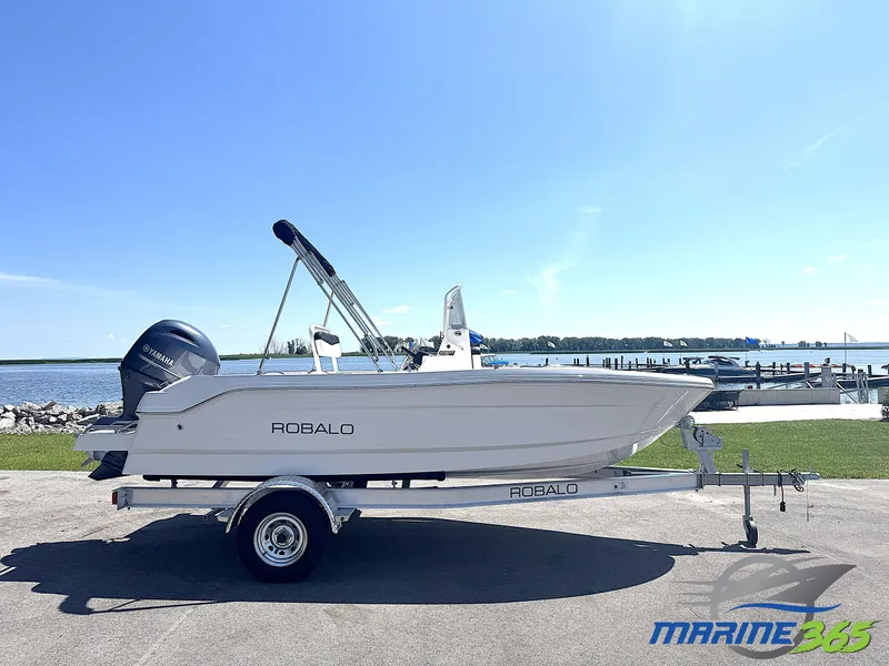 The Image of 2025 Robalo R160 Center Console boat on trailer by waterfront, clear blue sky. - 0