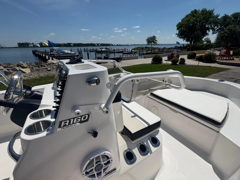 Slide: The Image of 2025 Robalo R160 Center Console boat docked by a scenic waterfront. - 12