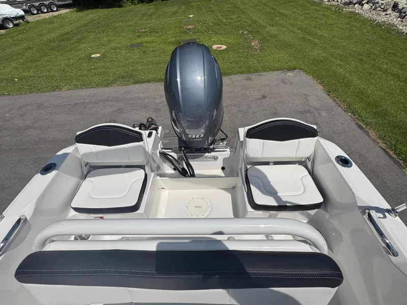 Slide: The Image of 2025 Robalo R160 Center Console boat with seating and outboard motor, parked on pavement. - 18