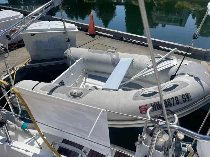 Slide: The Image of Inflatable dinghy docked beside Jeanneau Sun Odyssey 36, 1990 model, in a marina. - 12