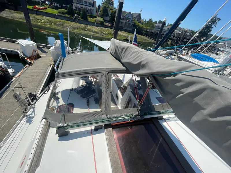 Slide: The Image of Jeanneau Sun Odyssey 36 sailboat docked, showcasing deck and covered cockpit, 1990 model. - 2