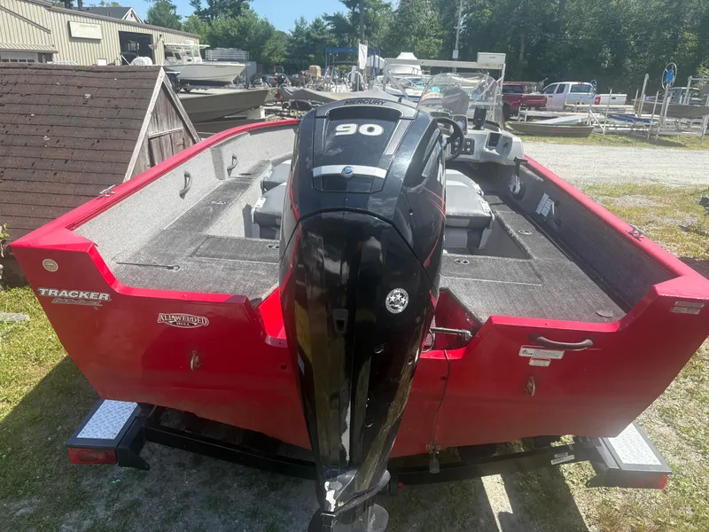 Slide: The Image of 2016 Tracker Pro Guide V-175 SC boat with Mercury 90 engine, red exterior, parked outdoors. - 2