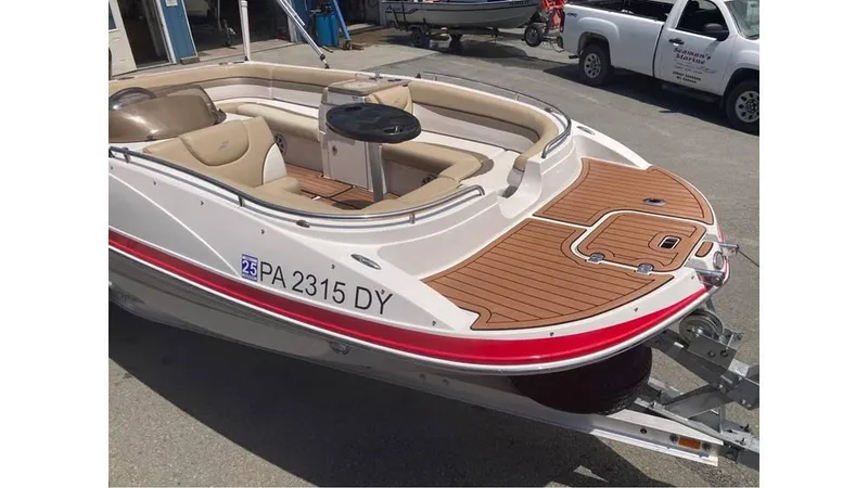 Slide: The Image of 2019 Starcraft MDX 191 O/B boat with tan seating and wood deck, parked on a trailer. - 4