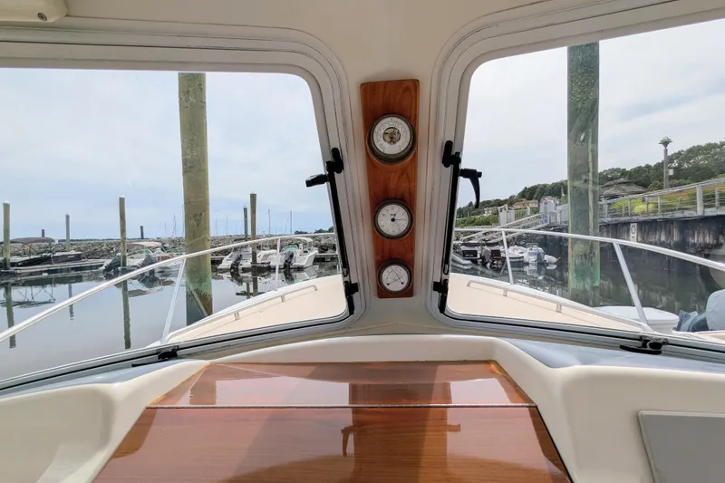 Slide: The Image of 2005 MJM 34z Downeast boat interior view, showcasing docked marina scene through windshield. - 18