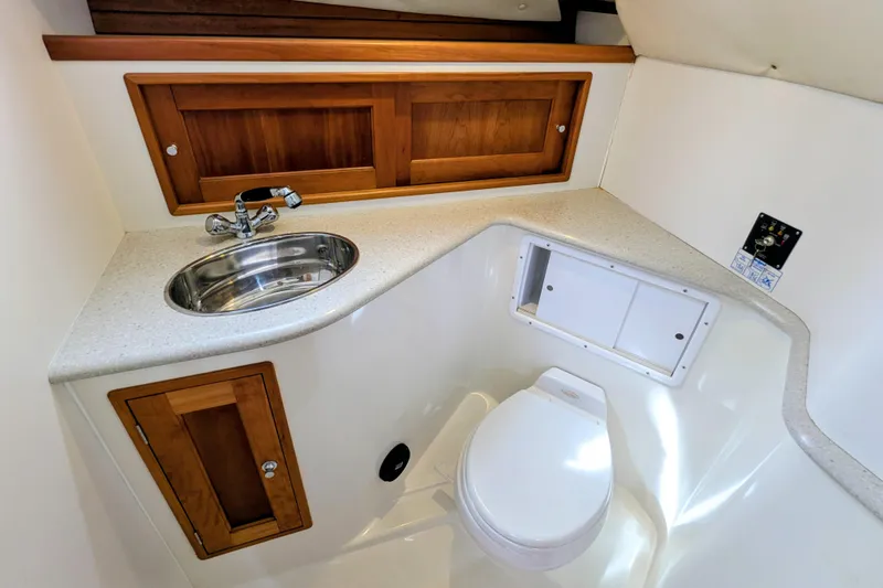 Slide: The Image of 2005 MJM 34z Downeast boat bathroom with sink, toilet, and wooden cabinets. - 28