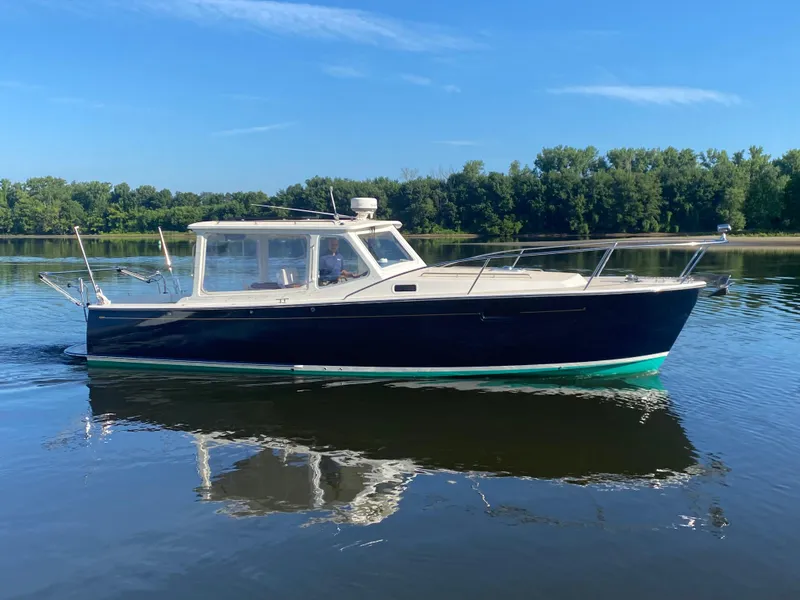 Slide: The Image of 2005 MJM 34z Downeast boat cruising on calm water with lush green trees in the background. - 4