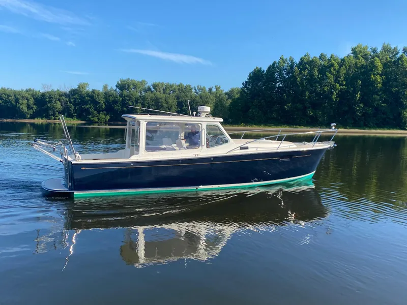 Slide: The Image of 2005 MJM 34z Downeast boat cruising on a calm lake with forested shoreline. - 5
